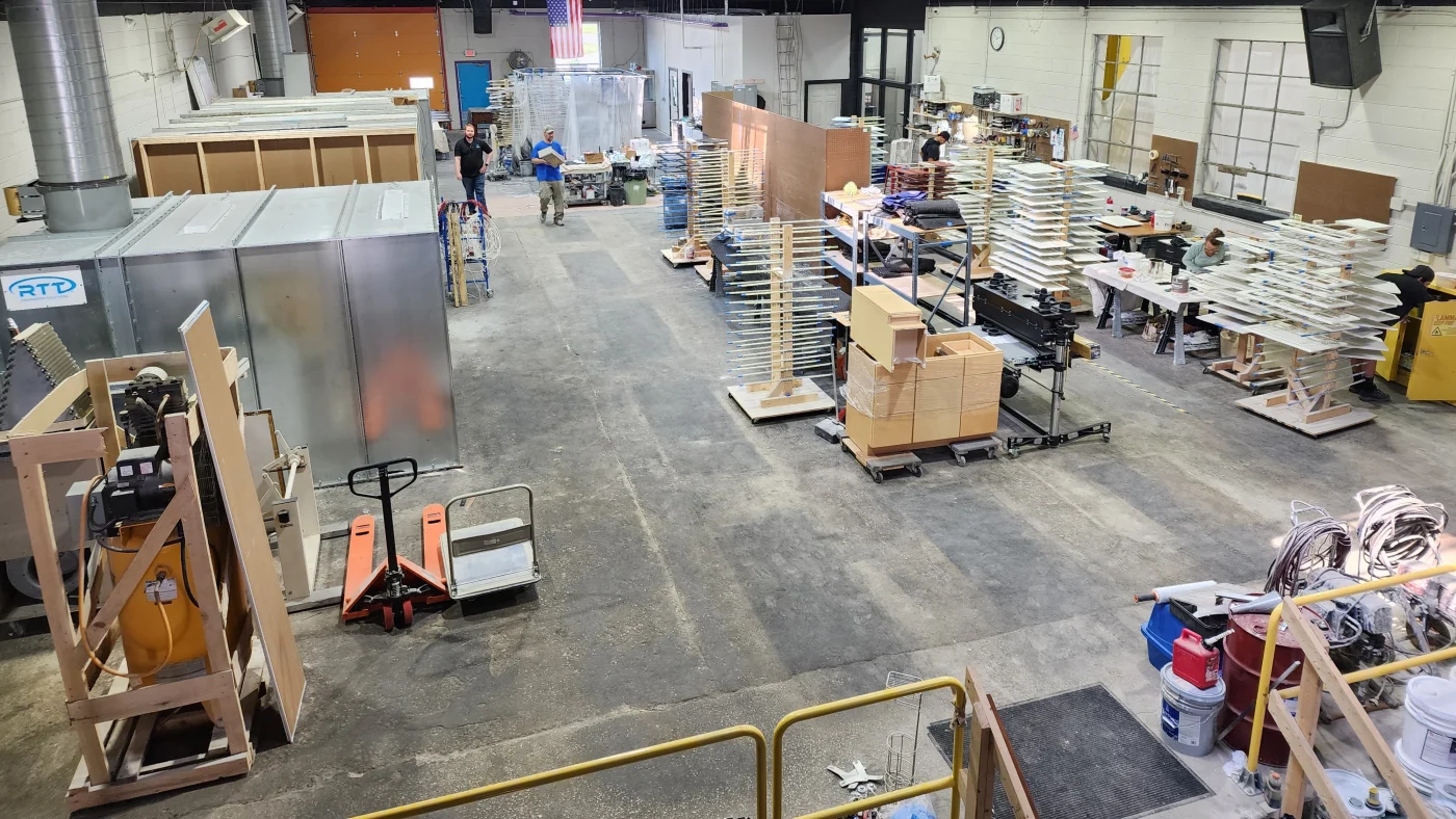 A view of the inside of the Colorwheel finishing and prefinishing workshop in Brookfield, showing many machines, tools, drying racks, products, booths, specialized ovens, and more.