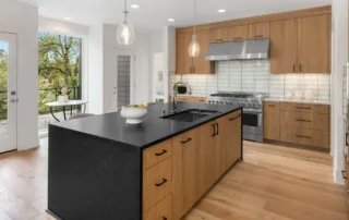 Modern Germantown kitchen with light hardwood flooring, black countertops, and beautiful wood cabinet refacing work done by Colorwheel Painting