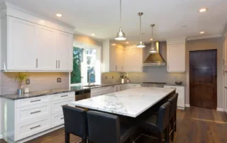 Kitchen with large marble island, wooden floors, and beautiful white cabinetry