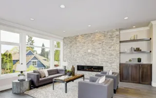 Home living room space with modern gray furniture and fireplace with newly painted bright ceiling and recessed lighting