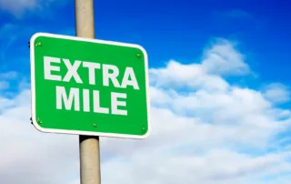 A street sign with the words “Extra Mile” against a blue sky