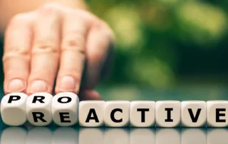 Blocks spell out the word REACTIVE but a hand turns the first few letters to change it to PROACTIVE