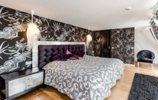 Bedroom with black and white wallpaper above headboard of bed