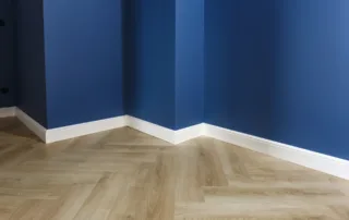 Bottom of dark blue walls with white trim; hardwood floors visible